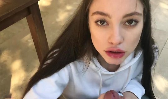 Длинноволосая брюнетка на коленках делает минет парню на камеру